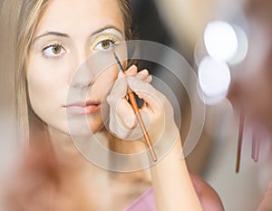 Young pretty woman getting make-up with brush.