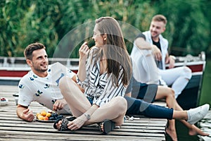 Young pretty woman and handsome man flirting while relax on picnic near river photo