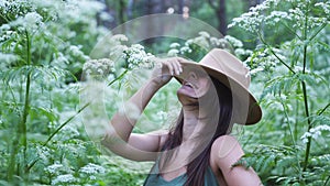 Young pretty woman in hat poses in deep forest among white flowers. slow motion