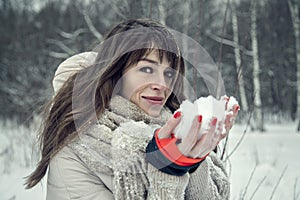 Young pretty woman having fun in the winter forest with snow in hands