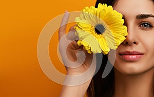 Young pretty woman hold yellow gerbera flower in green dress