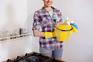 Young pretty woman holding cleaning tools and products in bucket