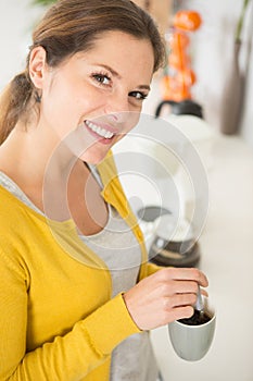 young pretty woman holding coffee spoon and stirring hot coffee