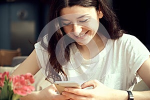 Young pretty woman holding and using smartphone, browsing internet, chatting online,