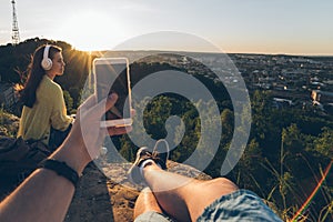 Young pretty woman listing music on the top of the hill with boyfriend