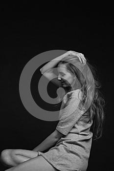 young pretty woman with long hair in dress sits and smiles on black background