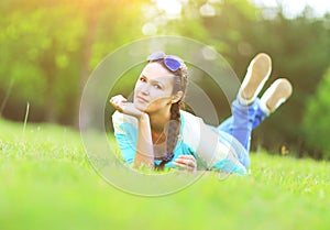 Young pretty woman lying on the grass at summer sunset