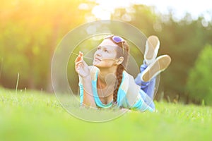 Young pretty woman lying on grass at summer sunset. Natural happiness, fun and harmony.