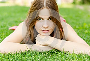 Young pretty woman lying on green grass in park