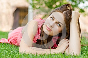 Young pretty woman lying on green grass in park