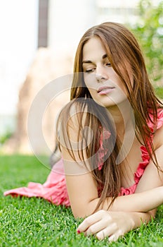 Young pretty woman lying on green grass in park