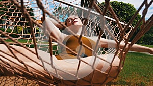 A young pretty woman lying in the hammock with closed eyes around tropical plants and having a rest