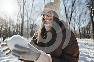 Young pretty woman making snowball outdoors in the park