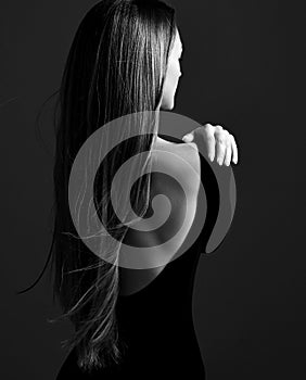 Young pretty woman model standing backwards in dress with open back and showing her gorgeous silky long straight hair