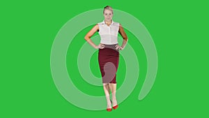 Young pretty woman model wolking with her hands on her hips on a Green Screen, Chroma Key.