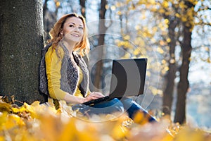 Young pretty woman in the park with laptop