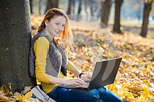 Young pretty woman in the park with laptop