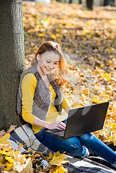 Young pretty woman in the park with laptop