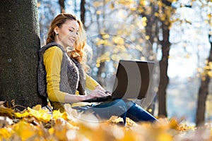 Young pretty woman in the park with laptop