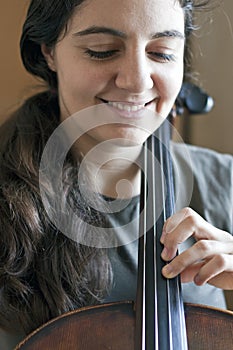 Young pretty woman playing violoncello