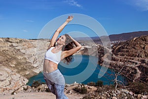 Young pretty woman is practicing yoga at mountain lake