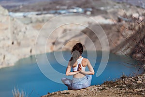 Young pretty woman is practicing yoga at mountain lake early morning.