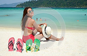 Young pretty woman in red bikini relaxing at the turquoise sea beach with summer fresh air