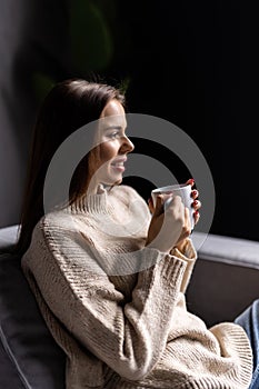 Young pretty woman relaxing on the couch and drinking from a mug at home