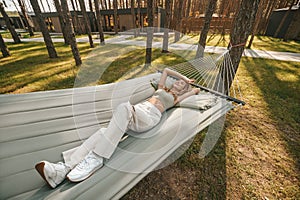 Young pretty woman relaxing in hammock in nature