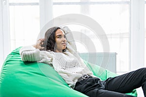 Young pretty woman relaxing on poof at home