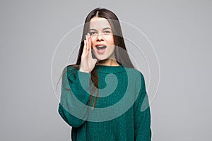 Young pretty woman scream wearing in green sweater isolated on gray background