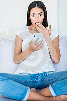 Young pretty woman sending message with smartphone on couch at home