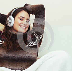 young pretty woman sitting in comfortable chair with coffee and blanket, winter season lifestyle people concept