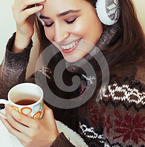 young pretty woman sitting in comfortable chair with coffee and blanket, winter season lifestyle people concept