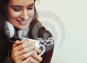 young pretty woman sitting in comfortable chair with coffee and blanket, winter season lifestyle people concept