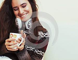 young pretty woman sitting in comfortable chair with coffee and blanket, winter season lifestyle people concept