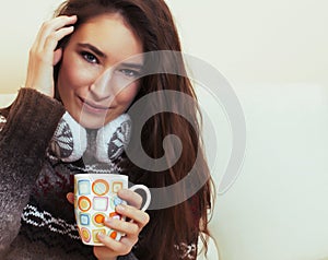 young pretty woman sitting in comfortable chair with coffee and blanket, winter season lifestyle people concept