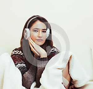 young pretty woman sitting in comfortable chair with coffee and blanket, winter season lifestyle people concept