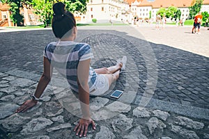 Young pretty woman sitting on the ground restting after long walk