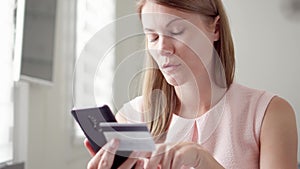 Young pretty woman sitting at home. Shopping online with credit card on mobile. Consumerism online