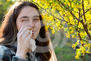 A young pretty woman smiles and is embarrassed by her Allergy to flower pollen. The concept of seasonal allergies and colds. Close