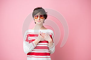 Young pretty woman  smiling and looking to camera with hands on chest and grateful gesture on face. Happy smiling woman feels