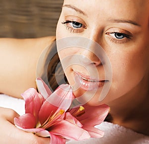 Young pretty woman in spa salon with manicure and lily flower close up smiling