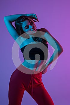 Young pretty woman in sport clothes possing standing isolated on pink light background
