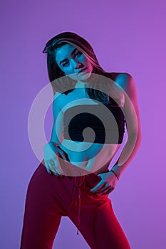 Young pretty woman in sport clothes possing standing isolated on pink light background