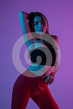 Young pretty woman in sport clothes possing standing isolated on pink light background