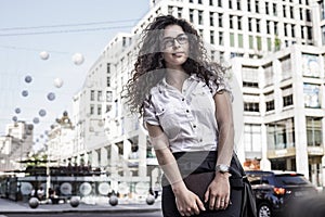 Young and pretty woman standing on the city background