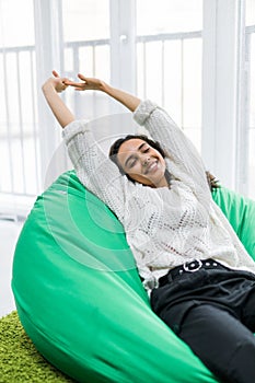 Young pretty woman stretching while lying on the poof at home