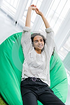 Young pretty woman stretching while lying on the poof at home