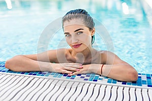 Young pretty woman in sunglasses looking at camera while swimming in pool